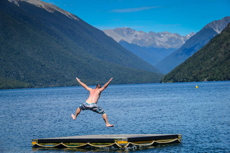 David Stock Jr of 8 Wonders of the World Adventure travel blog jumping off a dock at Nelson Lakes in New Zealand